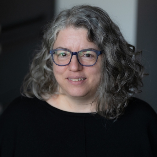 Photo of a woman with long hair and glasses.
